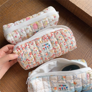 Detailed macro of three floral quilted cotton pouches with zippers on wood background