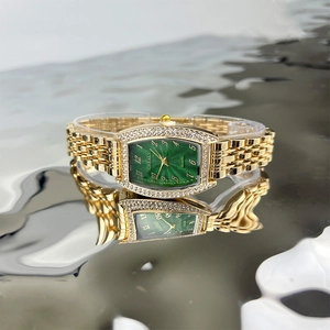 Macro shot of gold emerald quartz watch with crystal bezel on water reflection surface