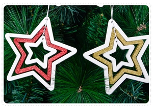 Close-up of red and gold wooden nested star ornaments hanging on a lush Christmas tree