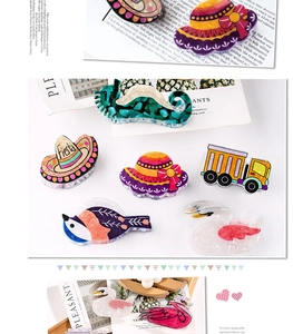 Close-up of creative acetate hair clips in shapes of cartoon hats, swans, and birds