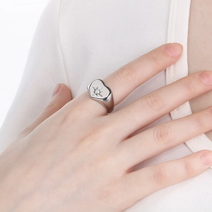 Close-up of heart-shaped silver ring with starburst diamond worn on a finger