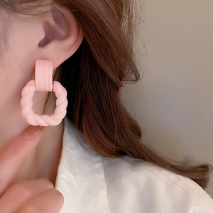 Close-up of pink acrylic geometric earrings worn by a model in soft lighting