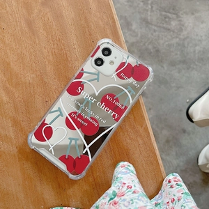 Detailed view of clear phone case with red cherry pattern and mirror finish on wood
