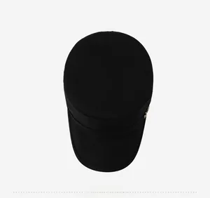 Top down view of a black cotton canvas cadet cap with flat crown and gold metal accent