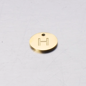 Close-up of a 12mm mirror polished golden stainless steel round pendant with letter H