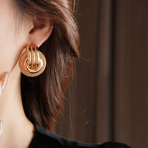 Close-up of golden mesh hollow round earrings on model with three polished rings