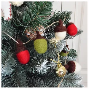 Detail von handgefertigten Wollfilz-Eicheln in Rot, Grün und Weiß am Weihnachtsbaum
