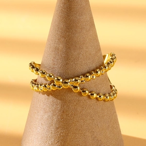 Close-up of golden double-layer cross ring with bead texture on a conical stand