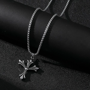Vue macro d'un pendentif croix en acier inoxydable argenté sur fond texturé noir