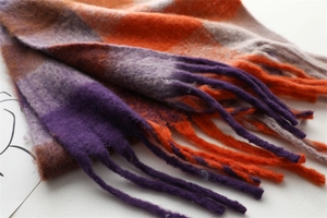 Close-up of thick winter scarf featuring rainbow plaid pattern and woven fringe detail