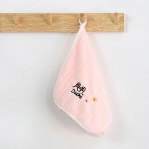 Pink coral fleece hand towel with duck embroidery hanging on a wooden hook