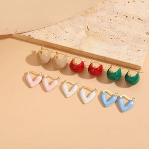 Detail view of heart-shaped enamel earrings in six colors on marble surface