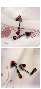 Detail of black titanium cat ear stud featuring red zircon and teardrop crystal dangle