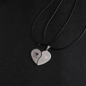 Gros plan de pendentifs cœur emboîtables noir et argent avec gravure love et YOU