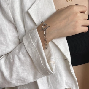 Macro detail of silver OT buckle chain bracelet worn on wrist with minimalist styling