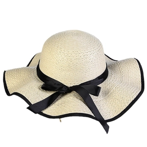 Women's summer straw sun hat with wide brim and black bow decoration on white background