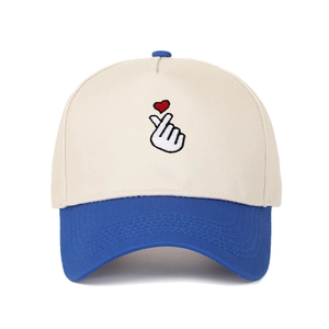 Detail of finger heart embroidery on beige and blue two-tone cotton baseball cap