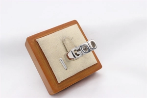 Detail of silver vintage GOD lettering ring on wooden stand with beige soft cushion