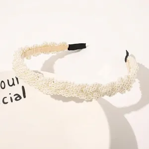 Detailed view of woven white pearls on a gold metal headband with comfortable ends
