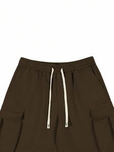 Dettaglio dei pantaloni cargo marrone scuro con vita elastica a coulisse e tasche laterali