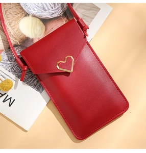 Detail of red textured leather crossbody phone bag with golden heart-shaped metal buckle