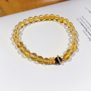 Detail of natural yellow citrine flower bracelet with golden clover charm on book page