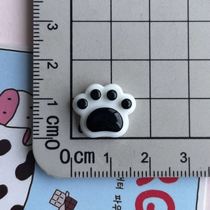 Macro shot of a 1.5cm glossy resin cat paw patch on a grid scale for DIY crafts