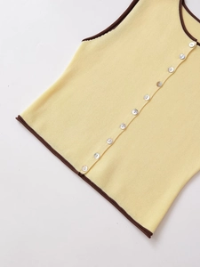 Détail de la maille fine et des boutons nacrés sur le haut sans manches jaune clair