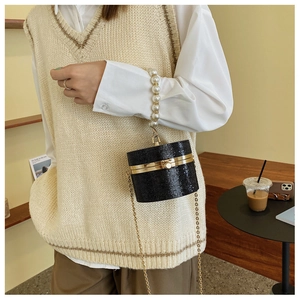 Detail of black beaded cylinder bag with pearl handle and golden chain strap