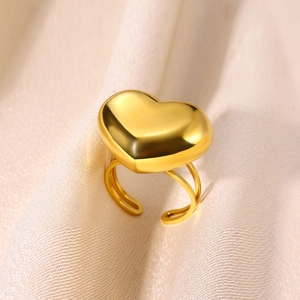 Polished gold heart stainless steel open ring on white satin fabric background