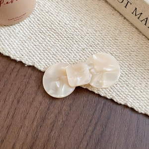 Detail of cream-white resin bow hair clip with marble texture on beige fabric background