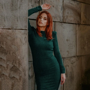 Close-up of sparkling dark green slim fit dress with long sleeves and elegant round neck