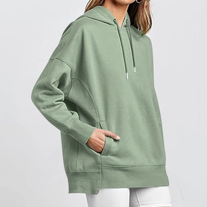 Detail of a Morandi green oversized hoodie featuring a kangaroo pocket and ribbed cuffs