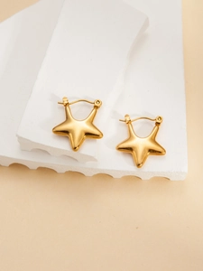 Detail view of gold star-shaped titanium earrings on a textured stone surface