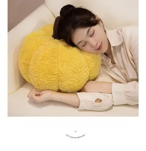 Detail of soft yellow plush pumpkin pillow used as a backrest on a white sofa