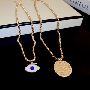 Vintage gold layered necklace with evil eye and hammered disc pendant on elegant background