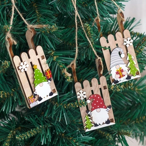 Three wooden Christmas gnome sled ornaments hanging on a festive green pine tree branch