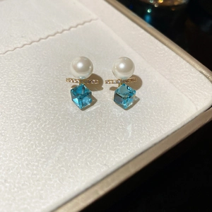 Detail view of 18k gold plated pearl earrings with green cubic zirconia in a jewelry box
