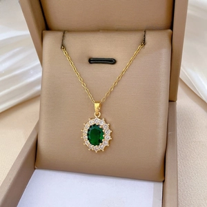 Detail of emerald oval pendant with sparkling diamonds on a gold chain in a jewelry box