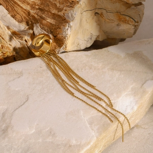 Detailed macro shot of a gold tassel ear cuff resting on a natural textured stone