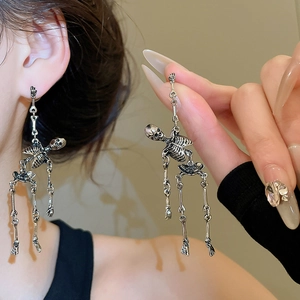 Detail of silver skull earrings with movable joints on a model in dark gothic style