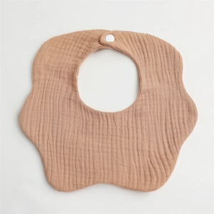 Detail of petal-shaped muslin baby bib in light brown soft cotton with snap closure