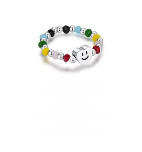 Détail d'une bague en perles colorées avec un pendentif coeur argenté et un smiley