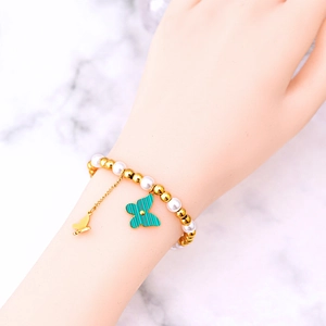 Elegant pearl and gold bead bracelet with peacock green butterfly pendant on model wrist