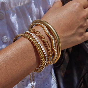 Gros plan de bracelets et chaînes superposés en acier inoxydable plaqué or 18 carats