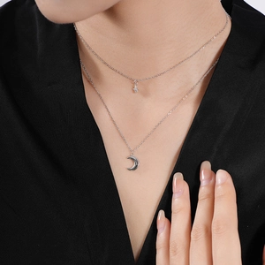 Close-up of S925 sterling silver layered necklace with star and moon pendants on model