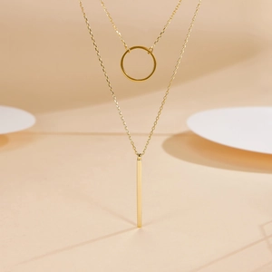 Detail of a minimalist gold layered necklace with circular and rectangular pendants