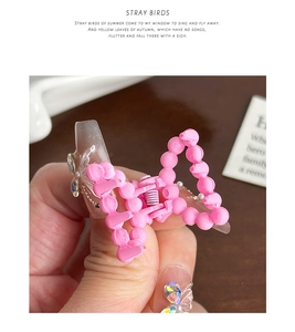Macro shot of a pink ribbon hair claw clip with beads held against a soft background