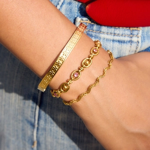 Ensemble de trois bracelets superposés en acier doré avec motifs floraux et pierres roses