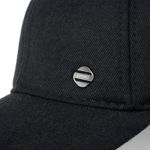 Detail of black cotton baseball cap showing silver SPORT emblem and twill fabric texture